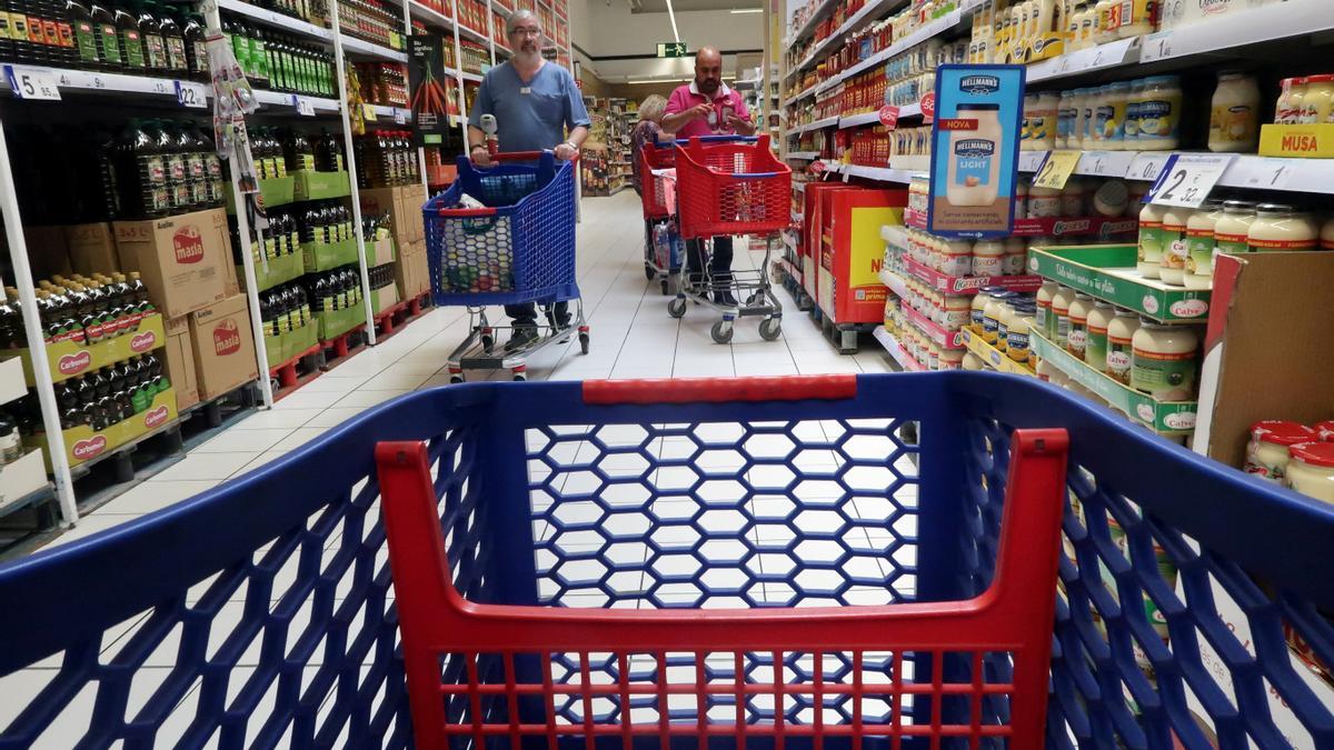 FILE PHOTO: People push a shopping cart in a Carrefour supermarket in Cabrera de Mar