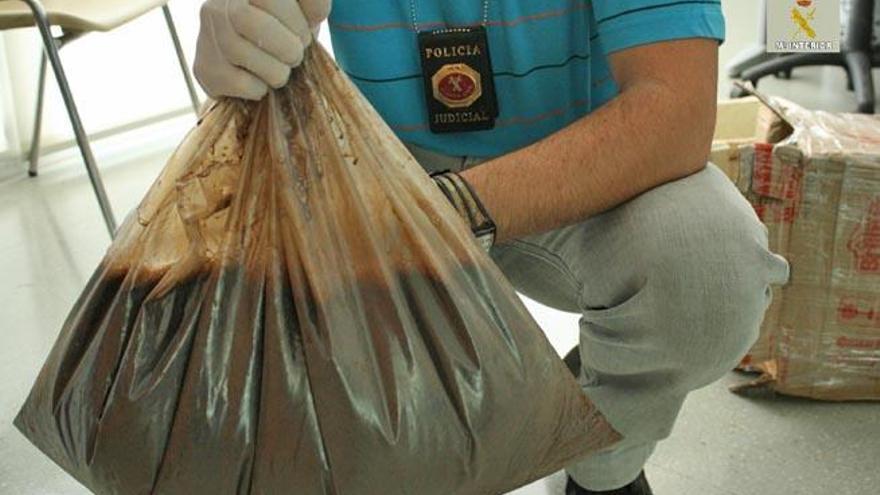 Un agente sostiene la bolsa que contenía 11.385 mililitros de ayahuasca.
