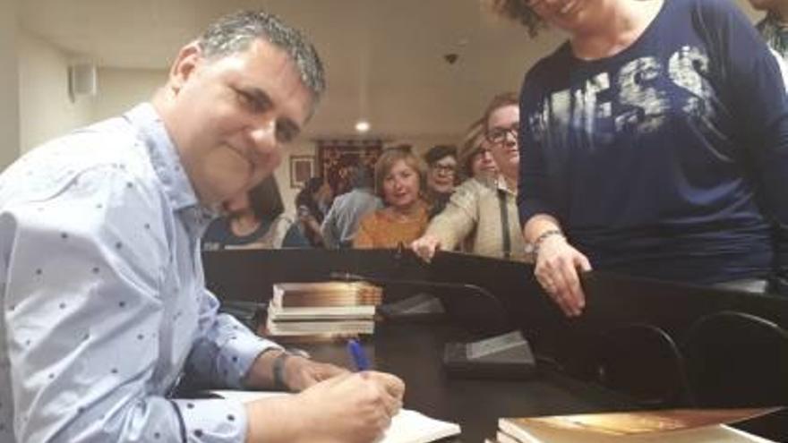 Mora firma ejemplares de su libro.