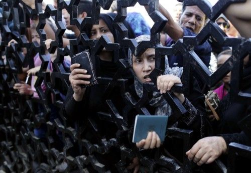 Palestinos de pie detrás de la puerta del cruce de Rafah mostrando sus pasaportes en su intento de cruzar a Egipto, en el sur de la Franja de Gaza.