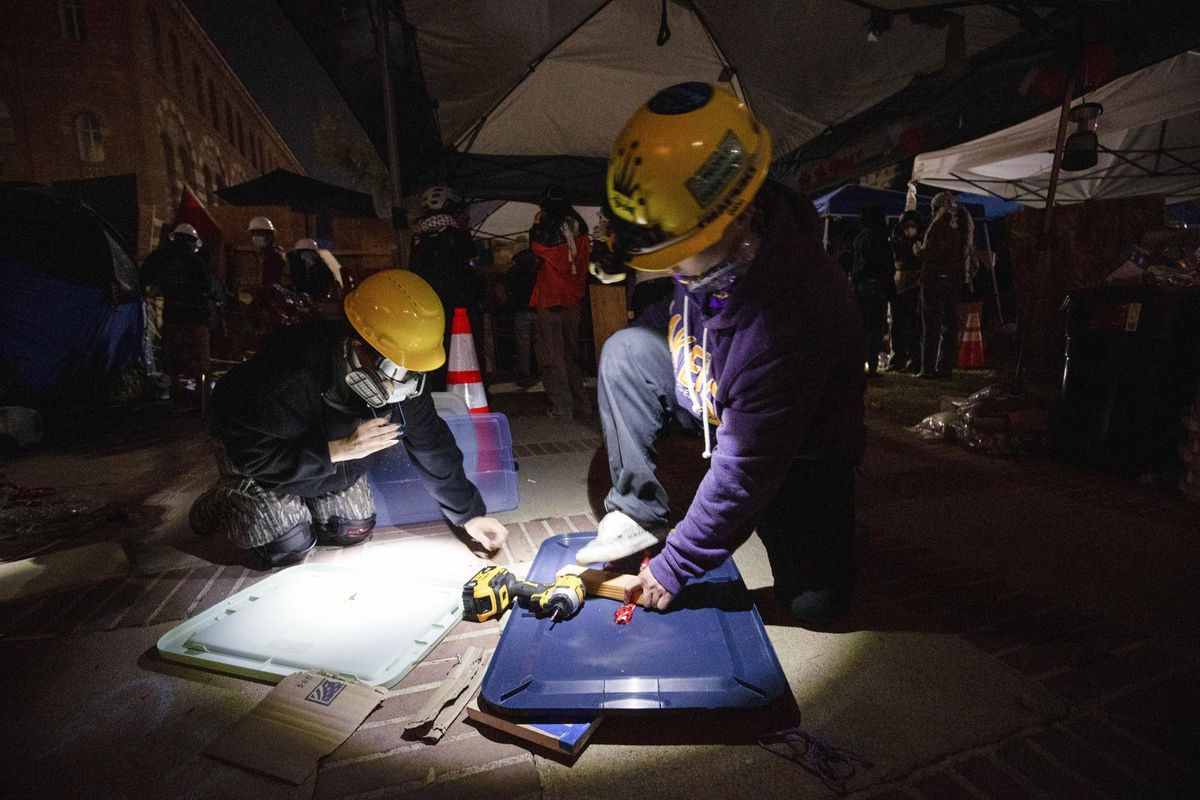 Pro-Palestinian demonstrators build makeshift shields in preparation for the possible clearing of an encampment by authorities on the UCLA campus Wednesday, May 1, 2024, in Los Angeles. (AP Photo/Ethan Swope)