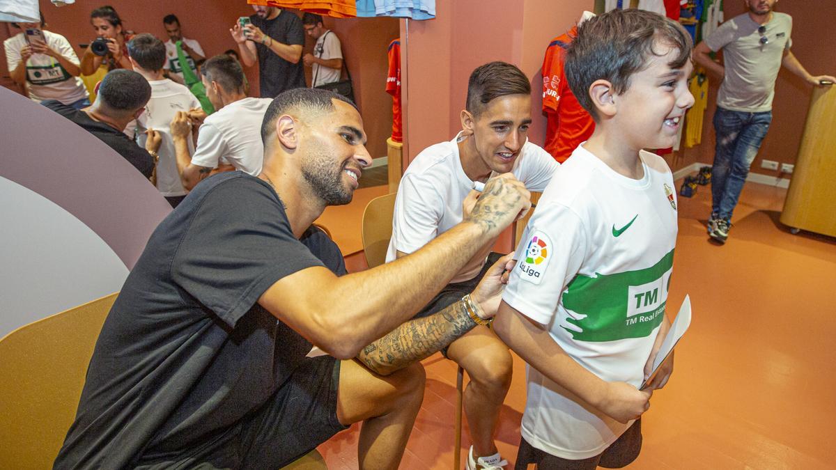 Omar Mascarell y Edgar Badia firmando una camiseta del Elche a un niño