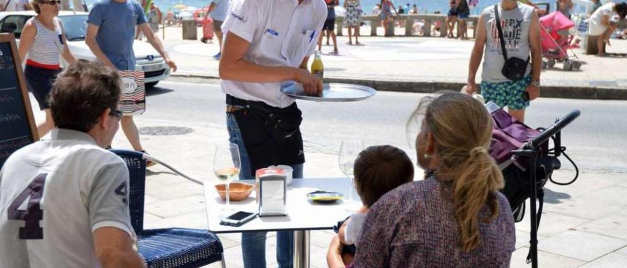 Un trabajador del sector de la hostelería en una terraza de la playa de Silgar, en Sanxenxo. // G. Santos