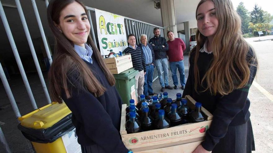 Paula Fernández, a la izquierda, y Jimena Ovies, con una caja de aceite para reciclar. Al fondo, Gonzalo Lasa, Agustín Díaz, su hijo Agustín y Marcos Lucena.