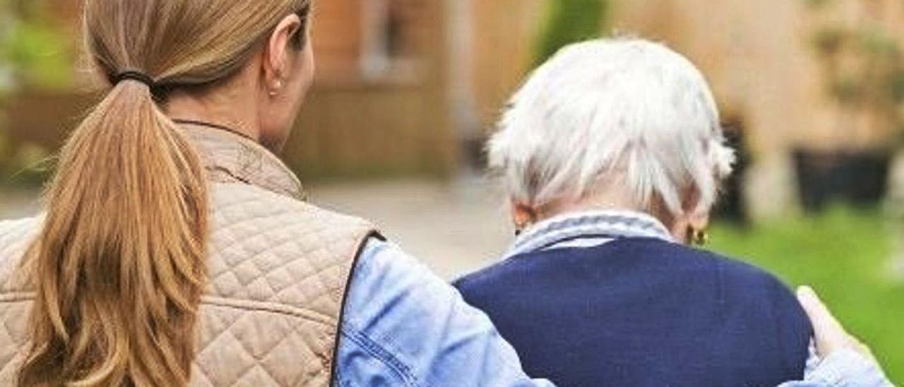 Una cuidadora acompaña a su familiar en un paseo al aire libre. | LEVANTE-EMV