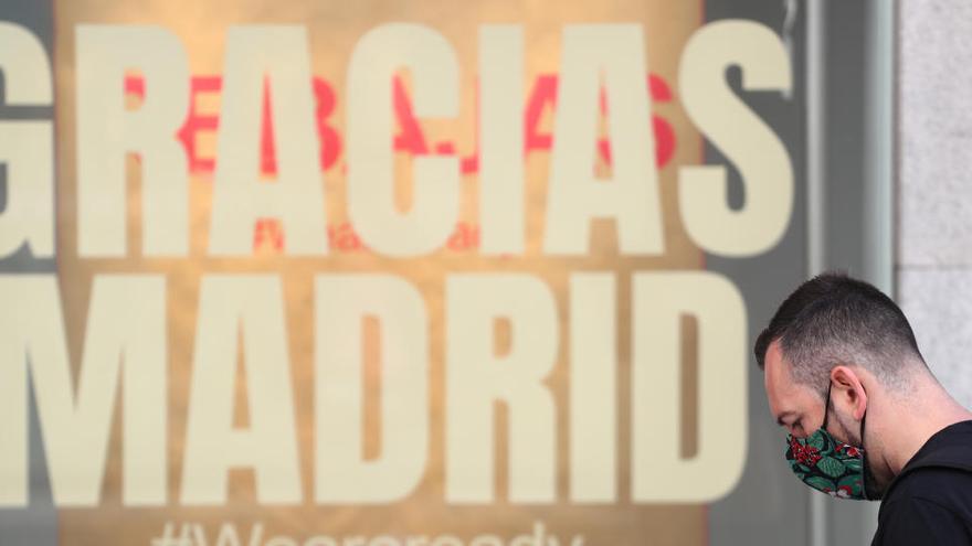 Un hombre pasa por delante de un escaparate con el mensaje &quot;Gracias Madrid&quot;.