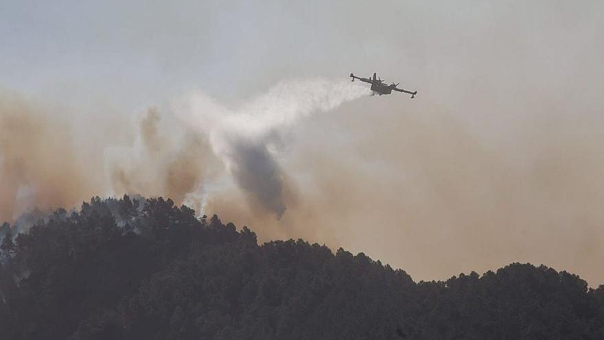 Un avión lanzando agua sobre las llamas en la mañana de ayer. | FRANCISCO CALABUIG