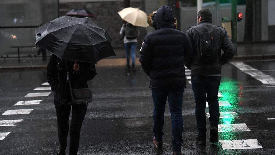 Varias personas bajo la lluvia en una calle de A Coruña.