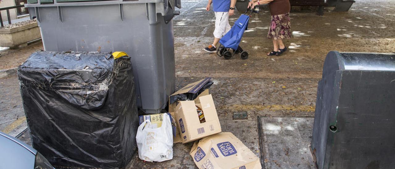 La plaza de España, llena de frutos desde hace días. Basura acumulada, enseres y cartones junto a los contenedores, y mobiliario urbano corroído por orín de perro.