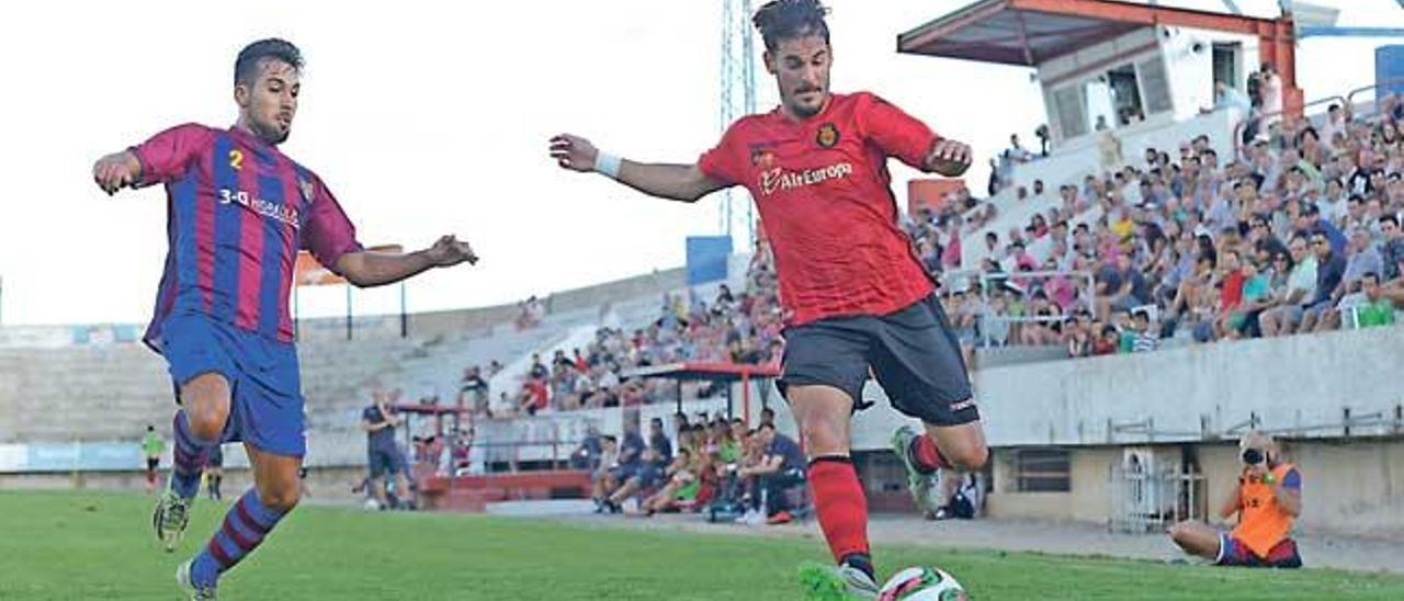 Joan Oriol trata de centrar ante la oposición de un rival del Poblense el domingo en sa Pobla.