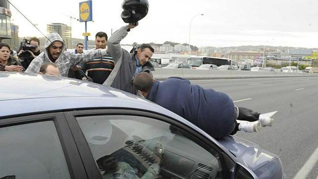 Un manifestante sobre el capó del coche en el momento que arranca. / víctor echave