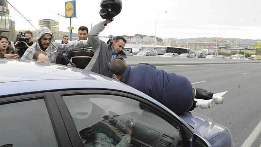 Un manifestante sobre el capó del coche en el momento que arranca. / víctor echave