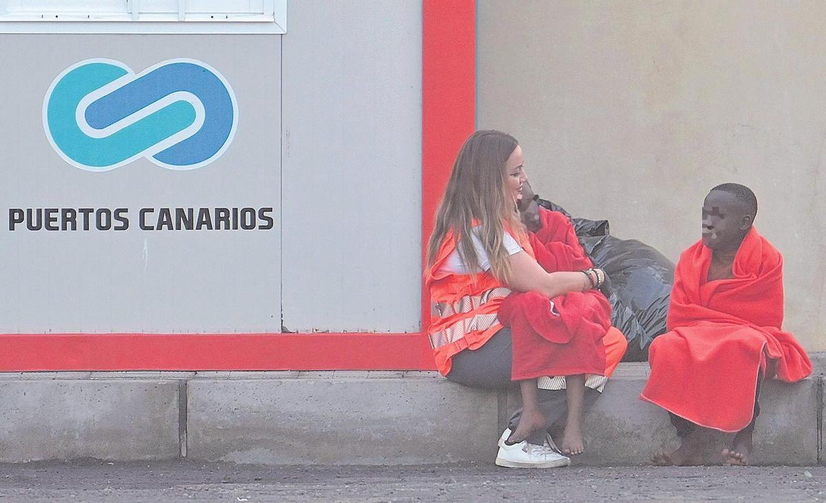 Imagen de archivo de una voluntaria de Cruz Roja junto a dos menores llegados en cayuco a El Hierro.