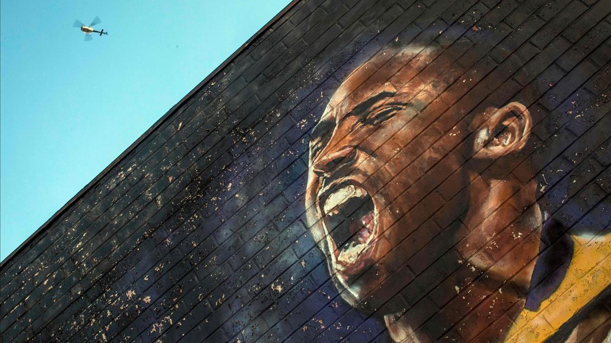 Un helicóptero sobrevuela un mural de Kobe Bryant en el centro de Los Ángeles el 26 de enero de 2020.  Nueve personas murieron en el accidente de helicóptero que cobró la vida de la estrella de la NBA Kobe Bryant y su hija de 13 años, confirmaron funcionarios de Los Ángeles