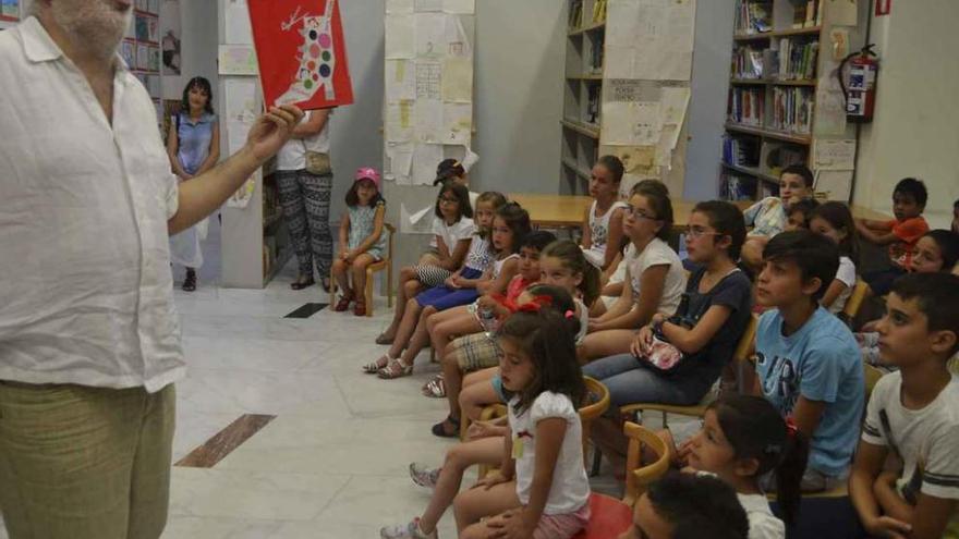 Fernando Martos (izquierda) sostiene un libro, y el bibliobús (derecha) a las puertas de la biblioteca, en los paseos de La Mota.