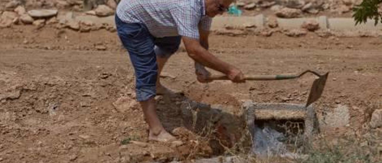 Un agricultor del campo de Elche abre una de las compuertas para regar su tierra.