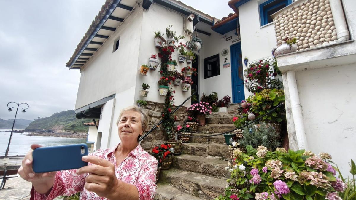Montse Rebollar Varas se hace un selfi delante de su vivienda, conocida popularmente como Casa El Rivero, en el puerto de Tazones (Villaviciosa), donde se inició la moda local de decorar con conchas de moluscos las macetas y paredes de las casas cercanas al muelle.
