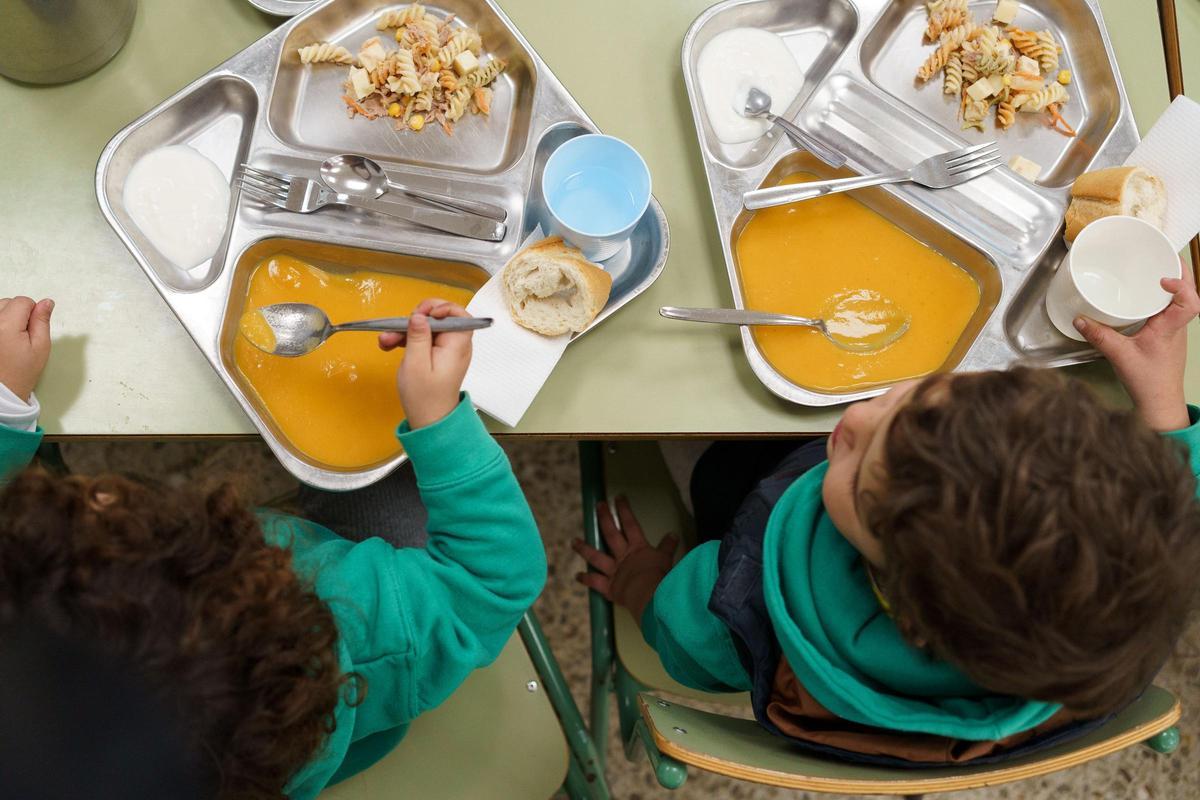 Dos niños comen en el comedor escolar.
