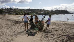 Unos niños participan en una campaña de recogida de basuraleza en la playa de Limens (Pontevedra).