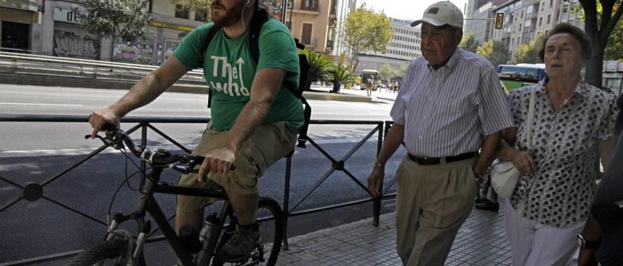 Imagen de archivo de un ciclista con auriculares y por la acera.