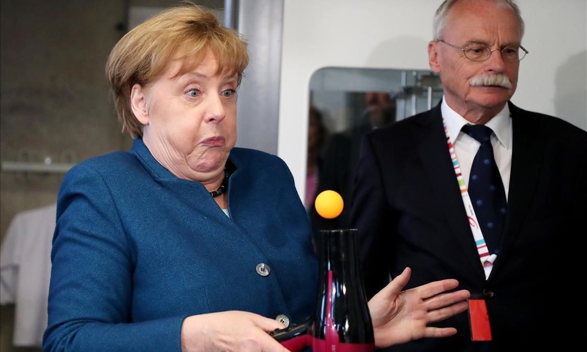 La canciller alemana, Angela Merkel, hace bolar una pelota de tenis de mesa con un secador durante su visita a una universidad, en Wuppertal (Alemania).