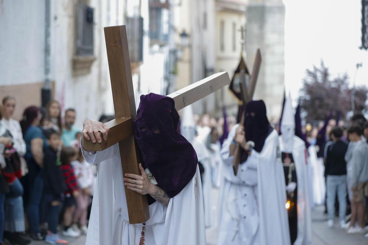 Penitentes cargan con su cruz en uno de los recorridos procesionales de la Pasión de Cáceres.