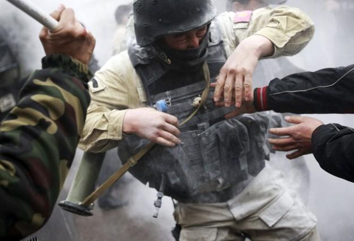 Protesters try to take a rocket propelled grenade from a riot policeman during clashes in Bixkek