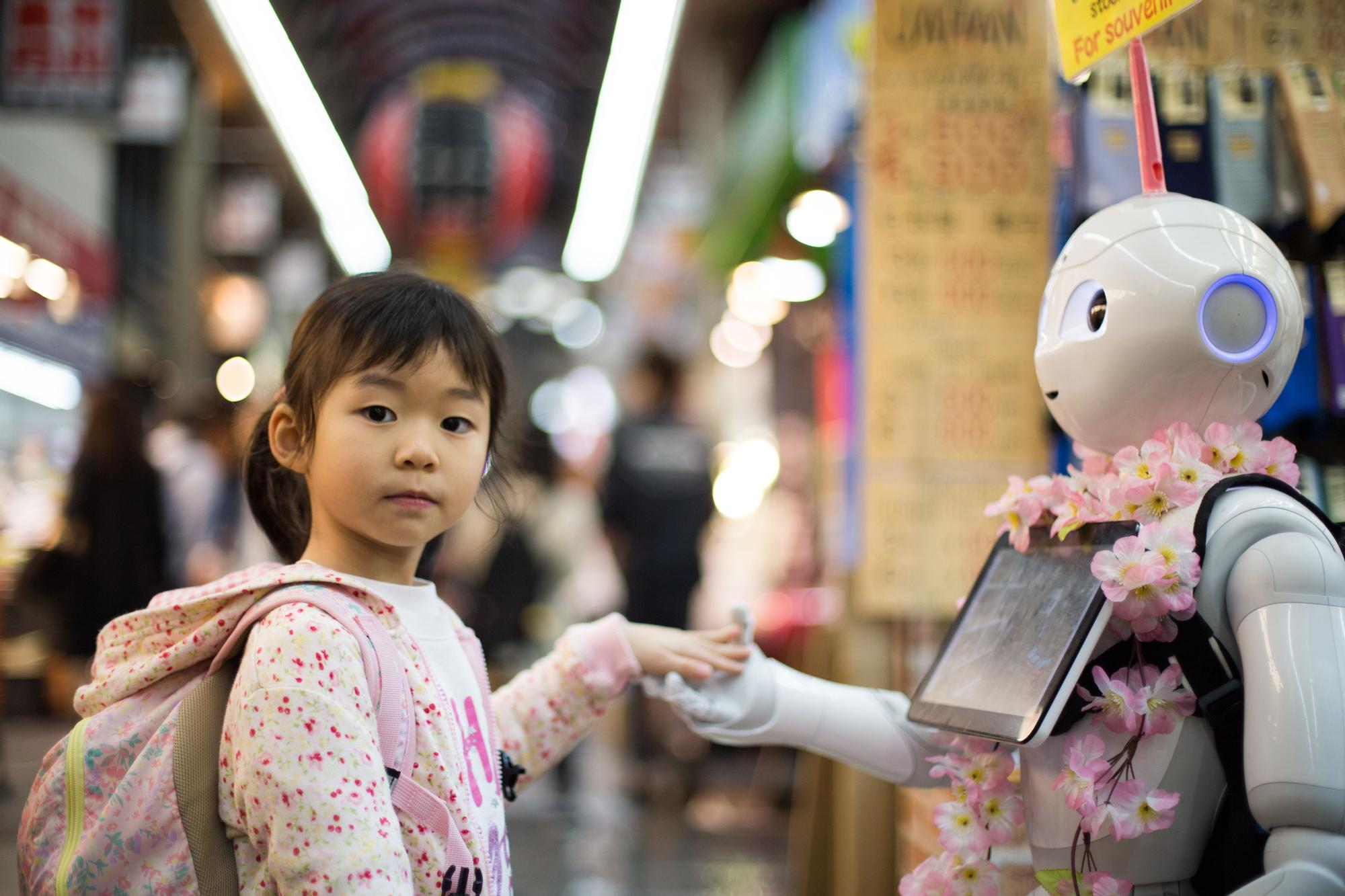 Un niña coge la mano de un robot en  Ōsaka-shi, Japan.