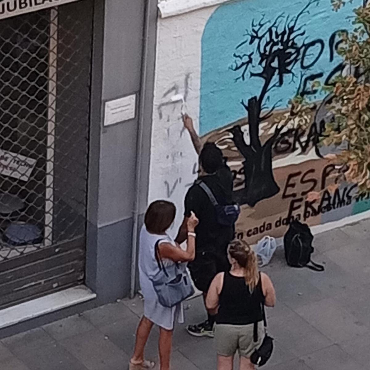 Los vecinos limpian las pintadas en el mural.