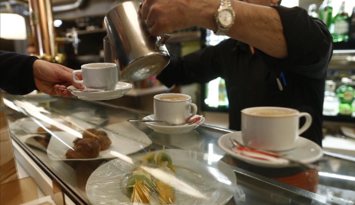 Un trabajador autónomo sirve café en un bar.