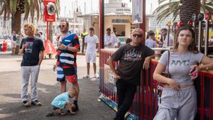 Personas en el race village de la Copa América, con vasos de aluminio, y mirando a las pantallas para seguir la competición.