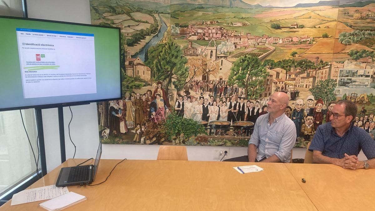 L'alcalde, Joan Carles Batanés (dreta) i l'arquitecte David-Aaron López, mirant un vídeo de com omplir el formulari