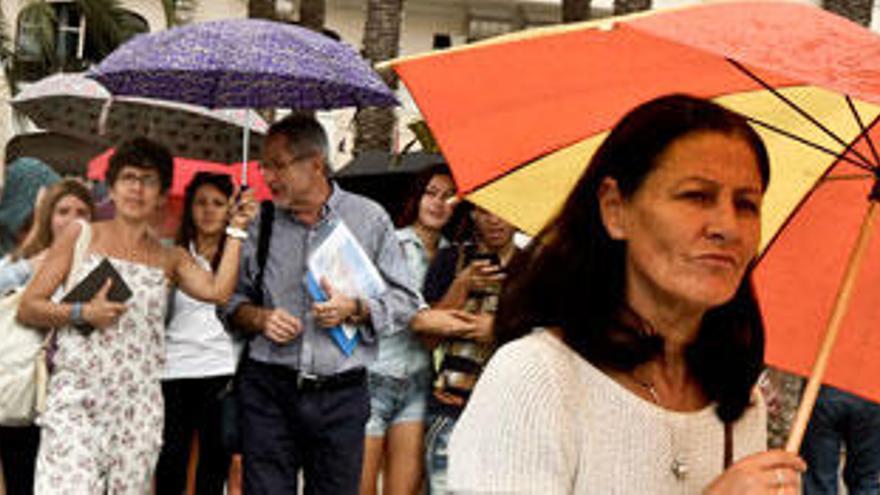 Ciudadanos se protegen de la lluvia esta tarde en el semáforo entre la Explanada y el Puerto de Alicante