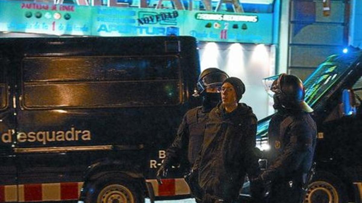 Dos mossos sacan a un ocupante de los multicines Laietana, tomados el sábado tras la manifestación.