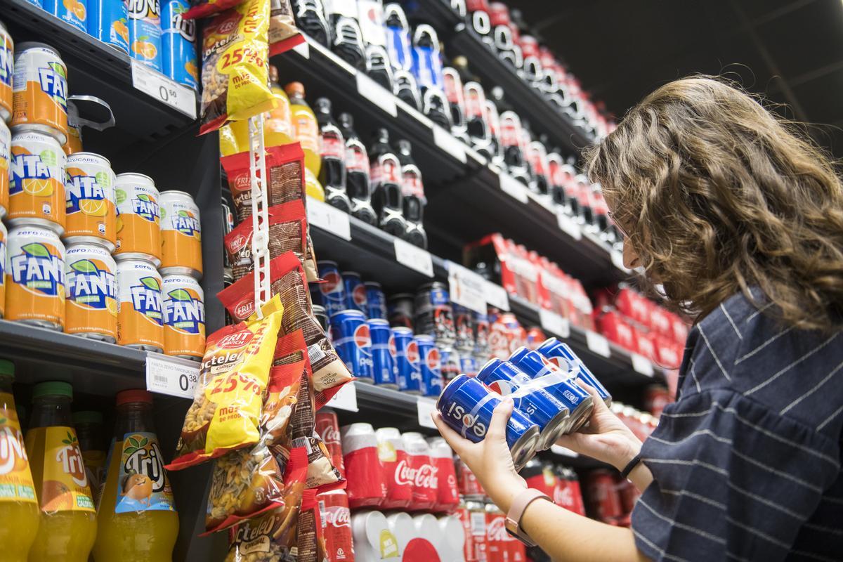 Una mujer, frente a los lineales de refrescos de un supermercado.