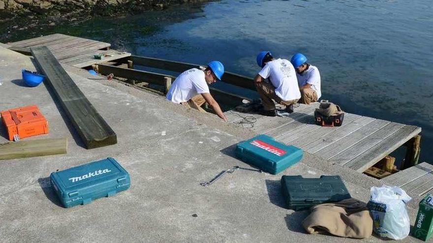 Alumnos de un programa de empleo que se impartió este año en Moaña arreglan la madera en el paseo marítimo. // S.A.