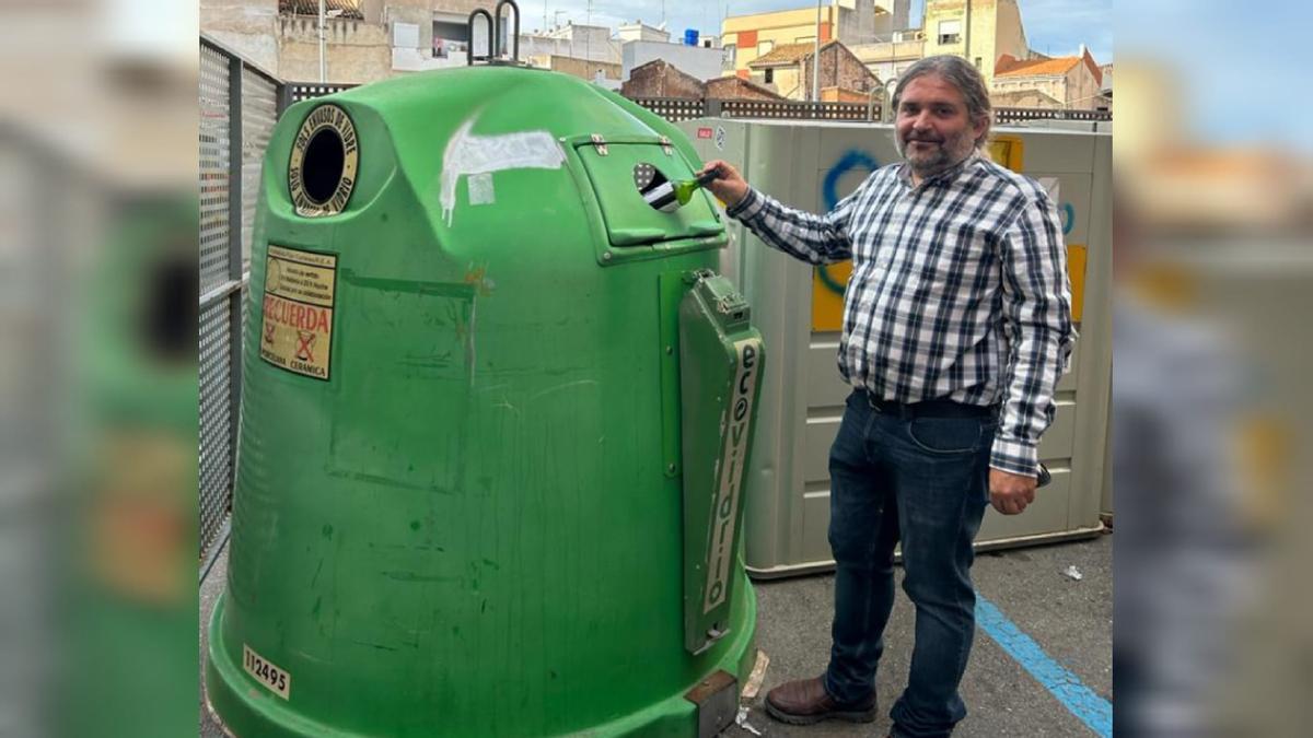 El concejal Bruno Arnandis recicla una botella en un contenedor de vidrio.