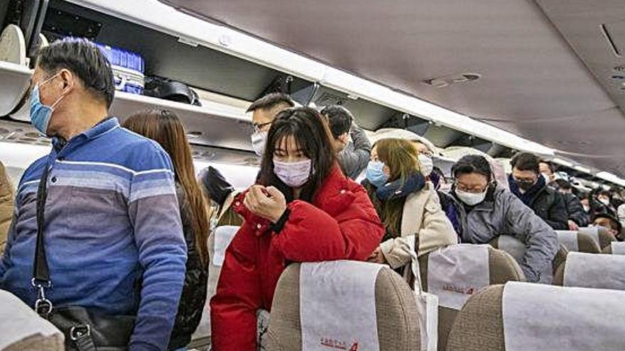 Viatgers amb mascaretes abans de desembarcar de l&#039;avió a Xangai, provinents de Jieyang.