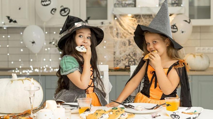 Dues nenes disfressades de bruixes mengen galetes