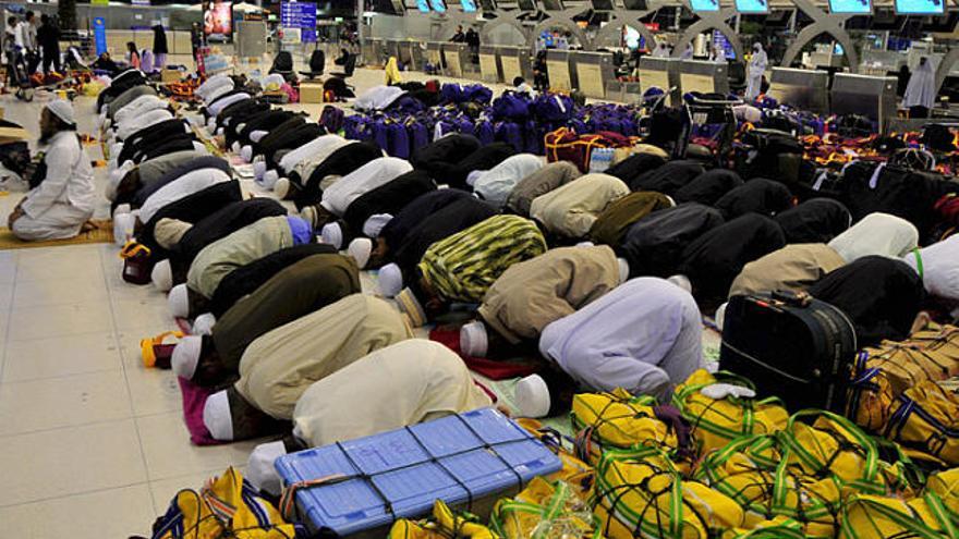 Un grup de musulmans prega en un aeroport ocupat de Bangkok.