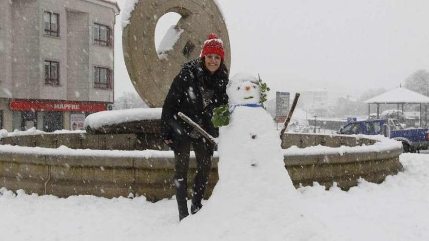 Una mujer junto a un muñeco de nieve, en la rotonda de A Roda, de Rodeiro. // Bernabé