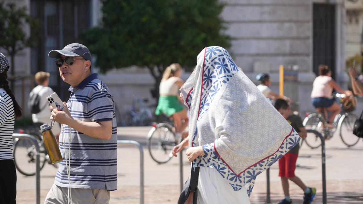 Dos personas caminan por la calle durante la cuarta ola de calor del verano