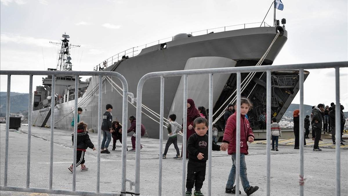 Niños, junto al buque militar que acoge a los refugiados y migrantes que llegaron a la isla de Lesbos en marzo.