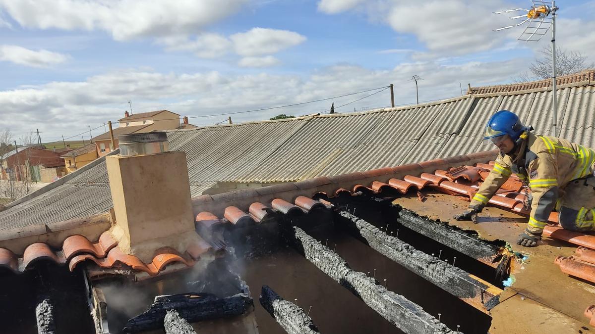 Un bombero revisa la cubierta y la parte superior de la chimenea en la que comenzó el fuego