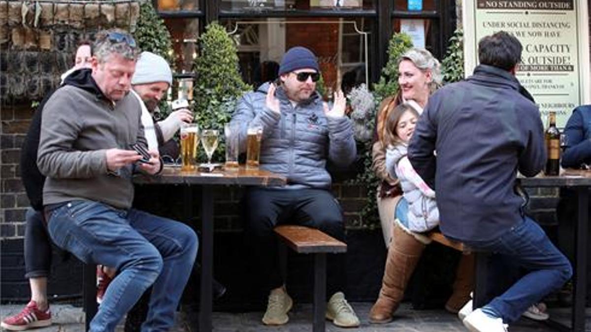 Ciudanos londinenses saborean su cerveza en un pub