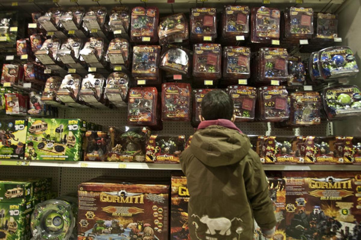 Un nen mira una prestatgeria plena de joguines en una botiga de Barcelona.