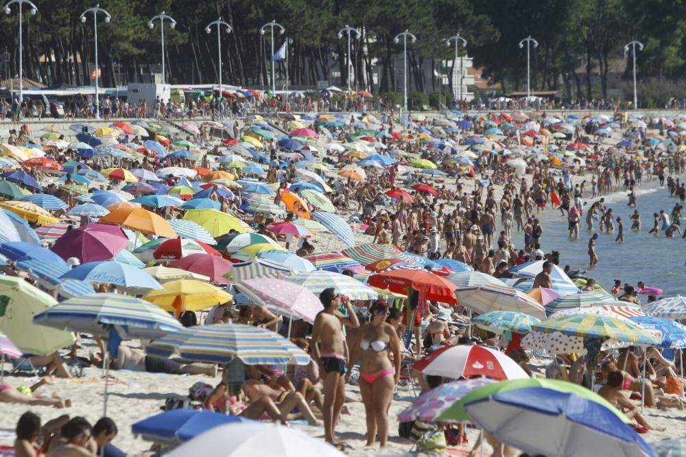 Una plaga de sombrillas irrumpe en Samil durante una jornada muy calurosa en el primer fin de semana de agosto