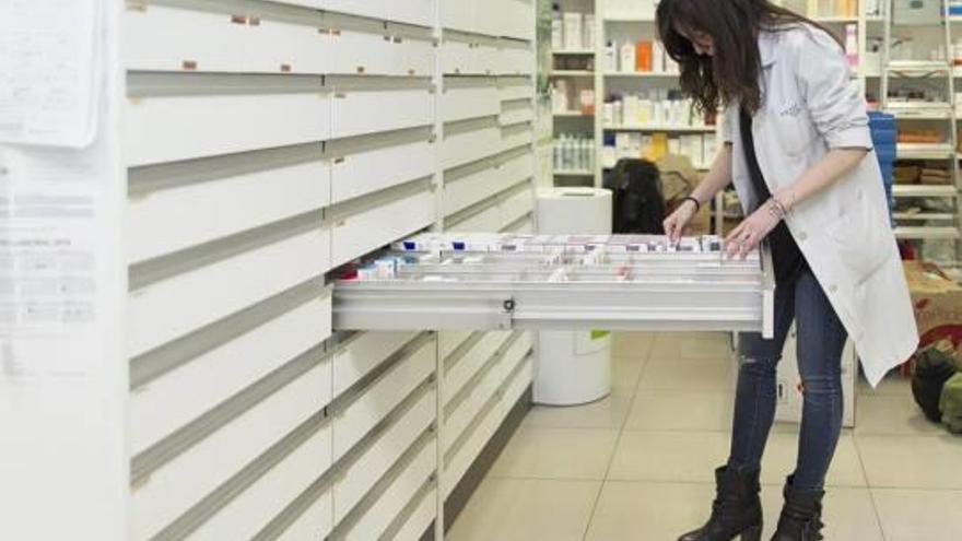 Una farmacéutica busca un medicamento en el almacén de una botica.