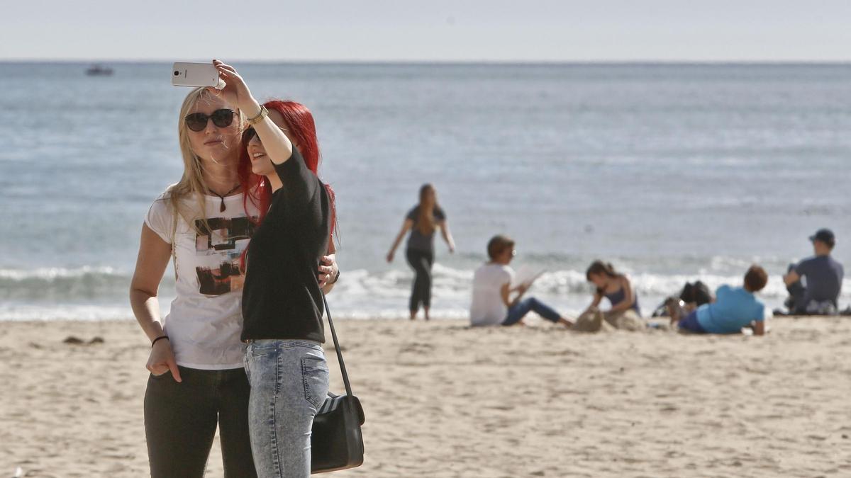 Dos jóvenes se hacen un selfi en la playa.