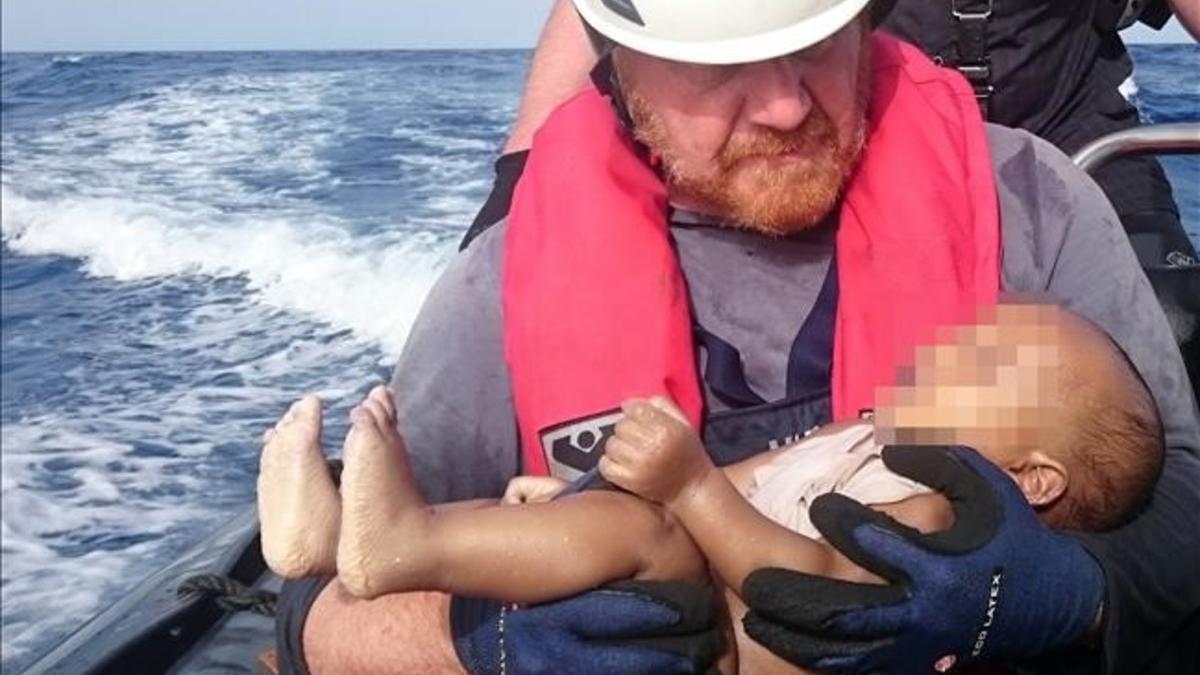 Un miembrod de la oenegé Sea Watch sostiene el cadáver de un bebé muerto recuperado de las aguas del Mediterráneo entre Libia e Italia.